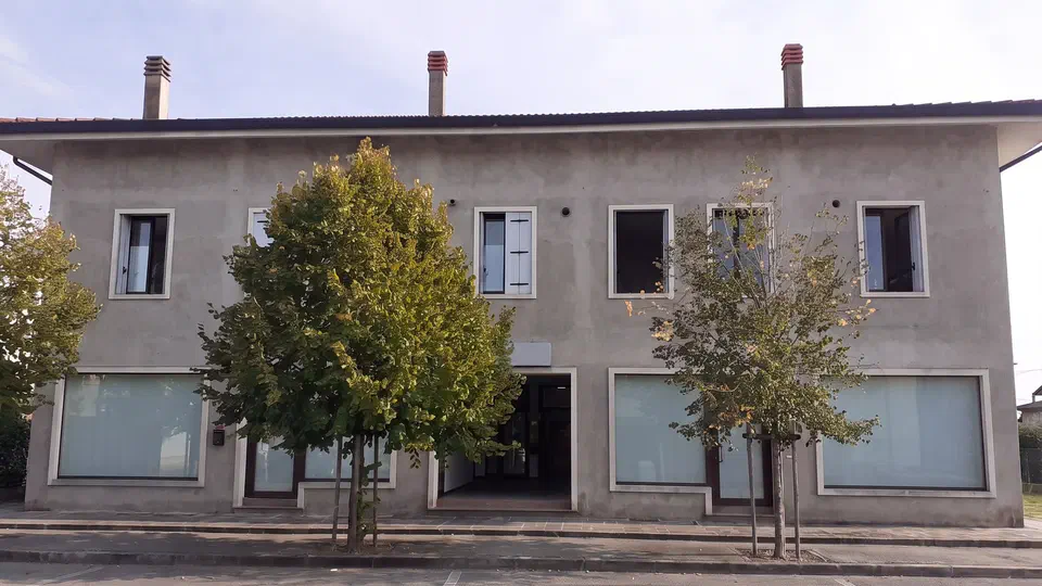 La facciata dell'edificio in Via Broli 29 dove si trova lo studio, con gli alberi lungo il marciapiede